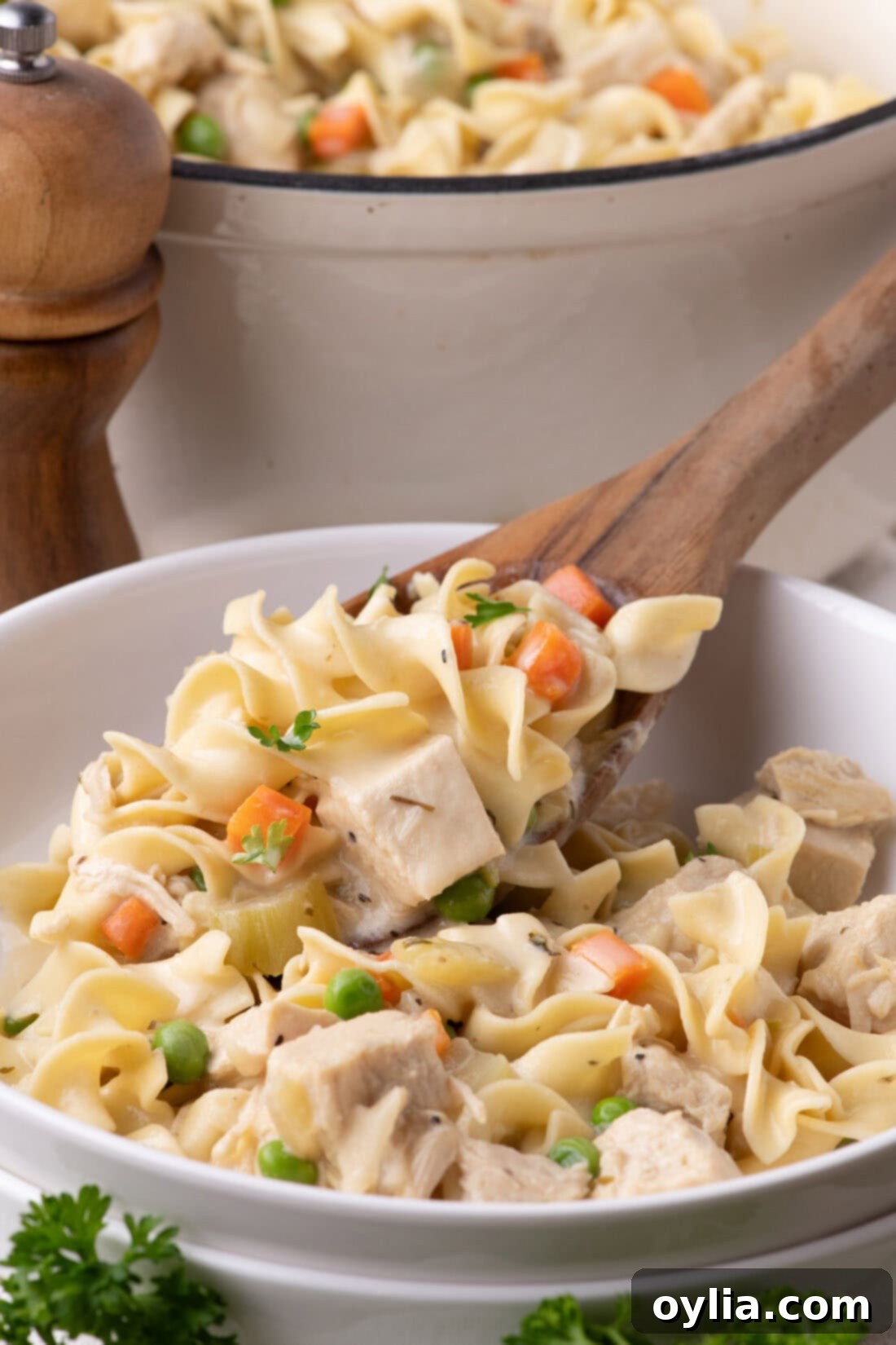 Chicken Pot Pie Pasta being spooned into a bowl, showcasing its creamy sauce, chicken, and vegetables.