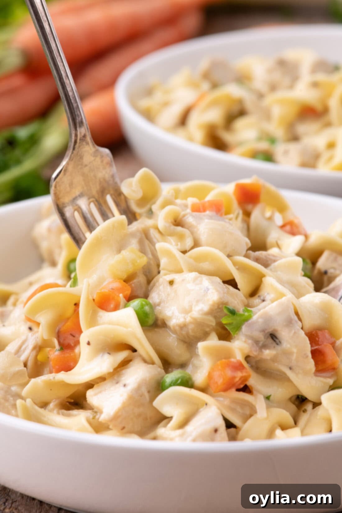 A fork digging into a bowl of creamy Chicken Pot Pie Pasta, highlighting the rich texture.