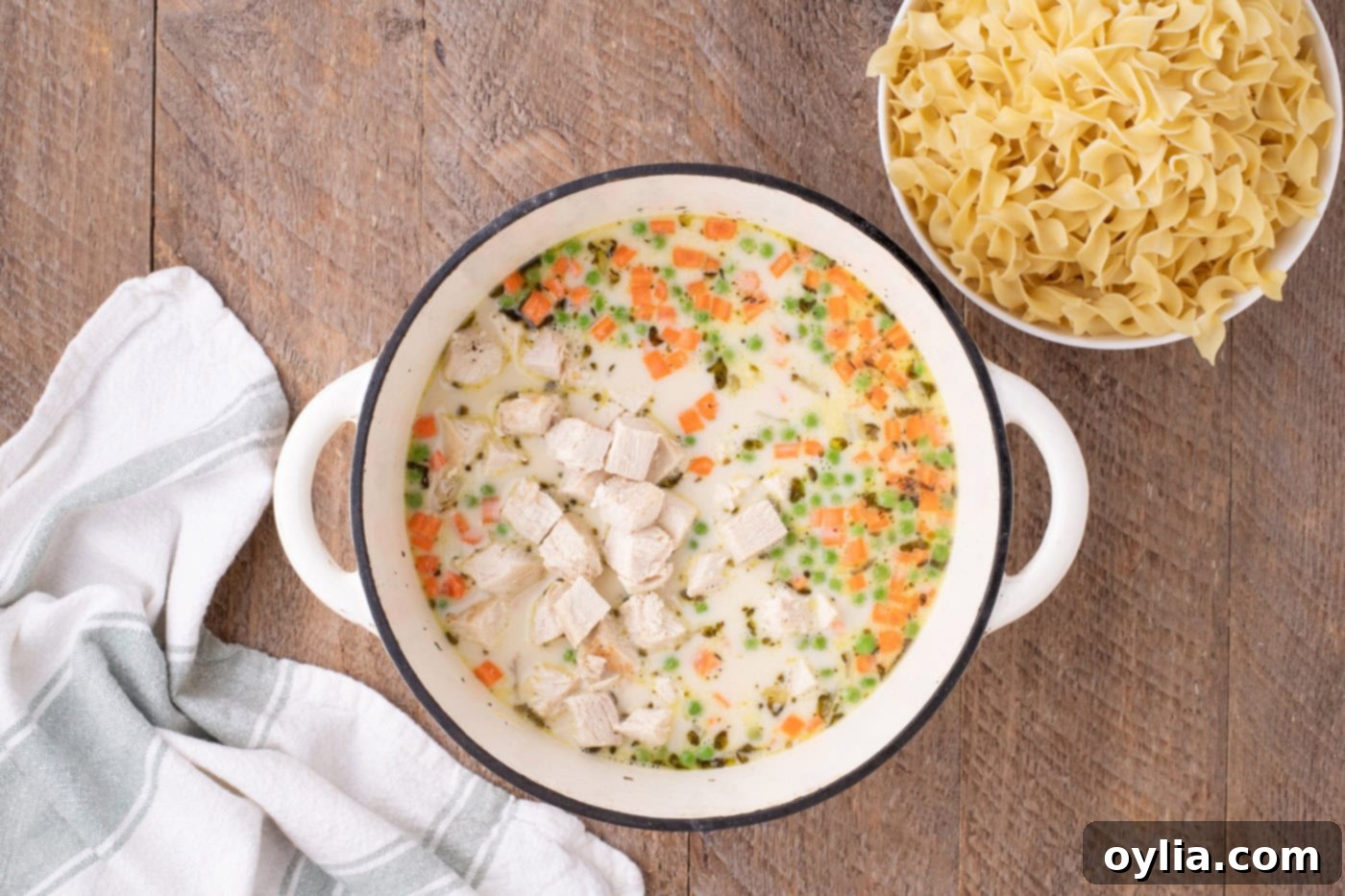 cubed chicken added to pot pie pasta in a pot