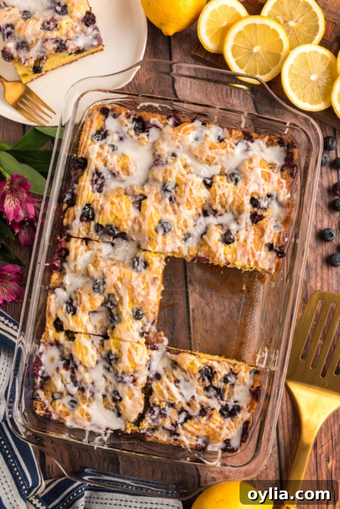Glazed Lemon Blueberry Cake with a slice removed, showing its moist texture and abundant blueberries.