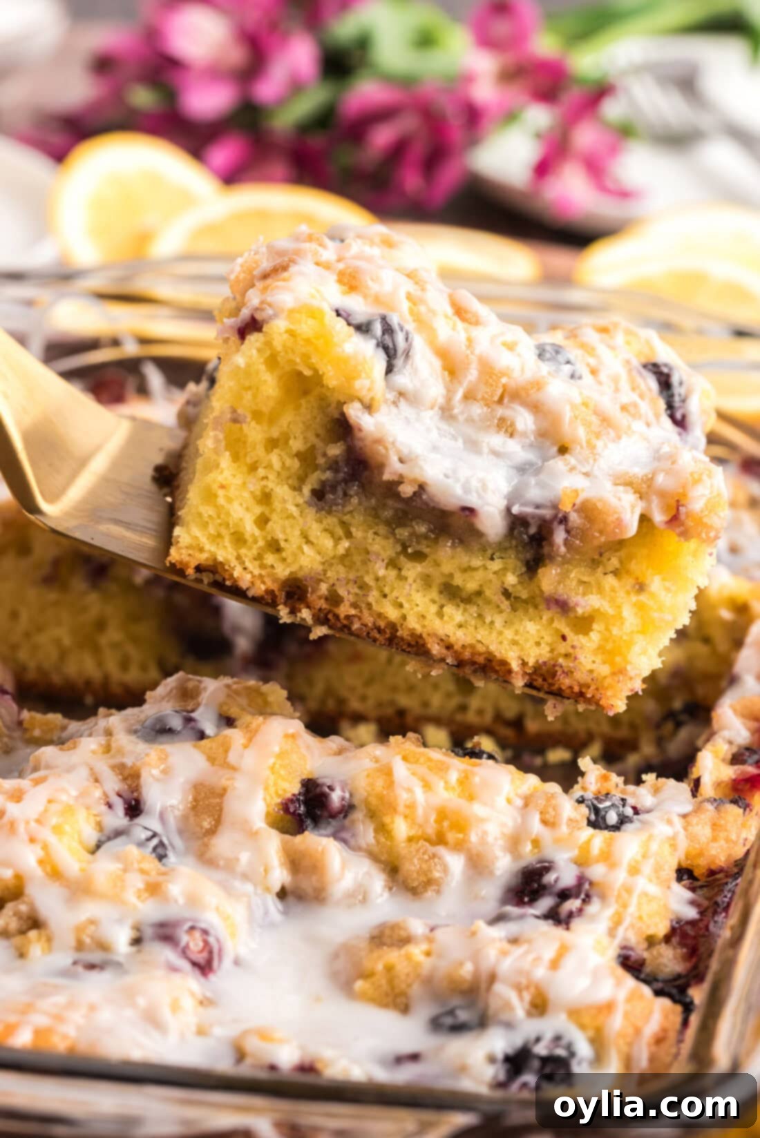 A slice of Glazed Lemon Blueberry Cake being carefully lifted out of the baking dish, revealing its perfect layers.