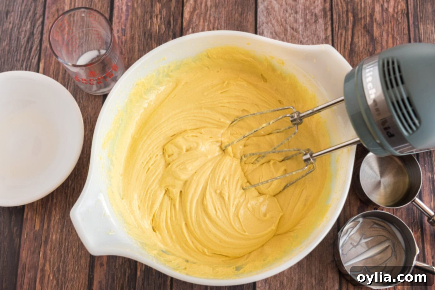 Lemon cake batter in a mixing bowl with whisk beaters, showing its smooth consistency.
