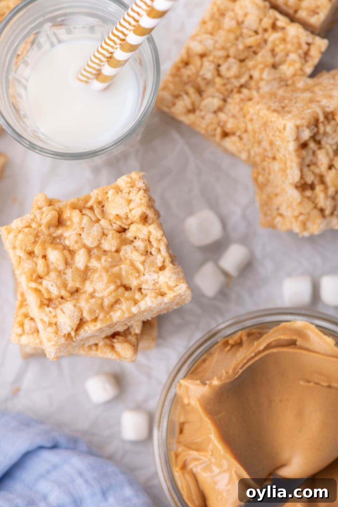 Chewy Peanut Butter Rice Krispie Bars 11 Stacked Peanut Butter Rice Krispie Treats with a bowl of peanut butter and a glass of milk to the side