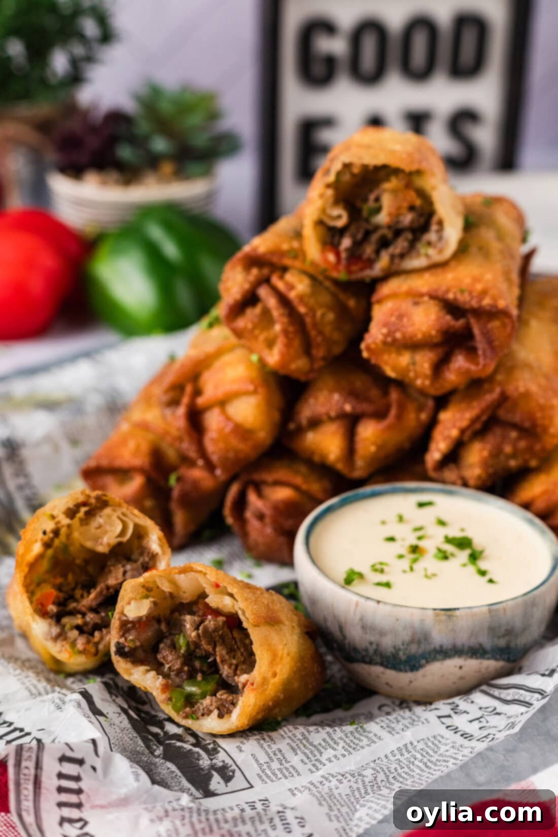 Stack of Philly Cheesesteak Egg Rolls with one cut in half revealing filling