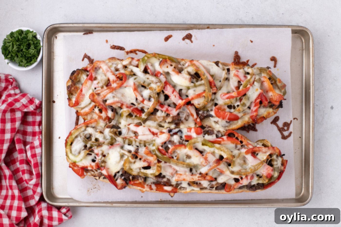 Overhead view of a baked Philly Cheesesteak Cheesy Bread loaf, golden and bubbly from the oven.