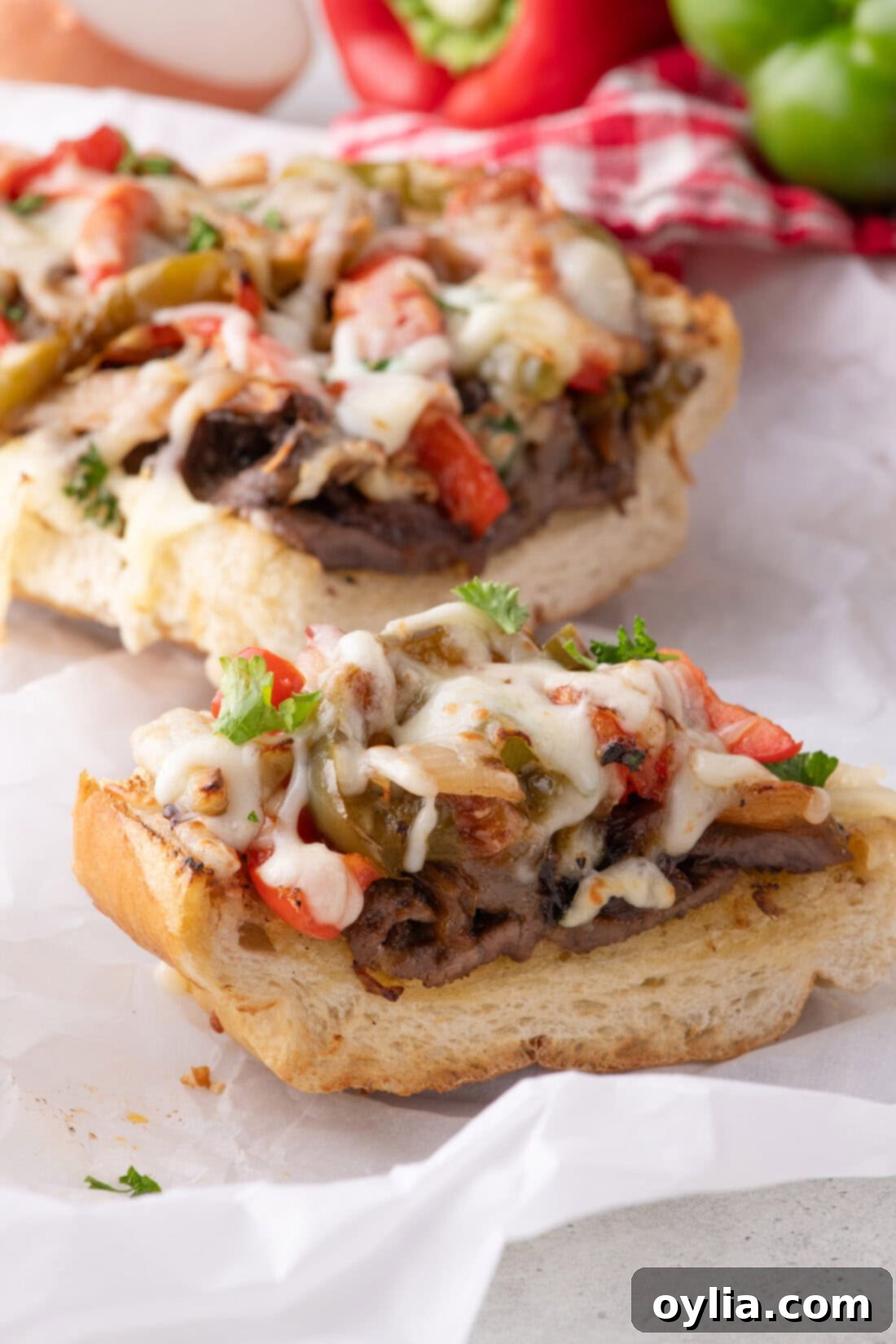 Close up photo of a single slice of Philly Cheesesteak Cheesy Bread, showing the intricate layers of meat, vegetables, and melted provolone.