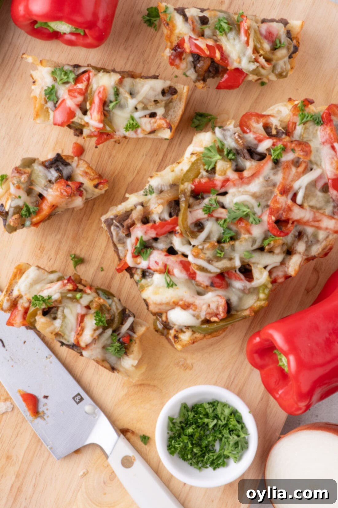 Philly Cheesesteak Cheesy Bread cut into slices on a wooden cutting board, ready to serve.
