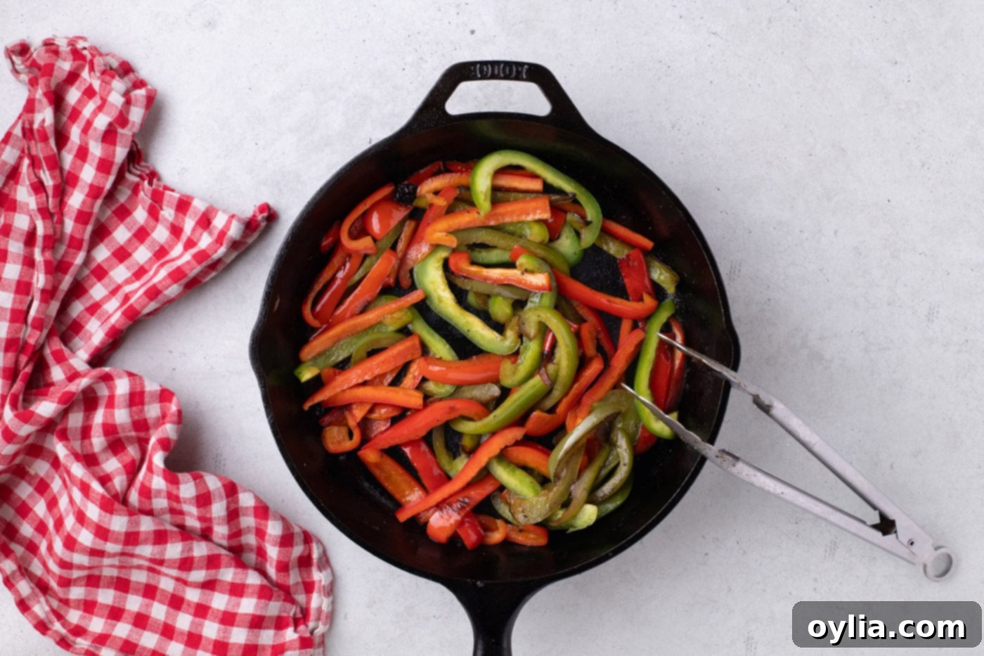 Red and green bell peppers cooked and softened in a skillet.