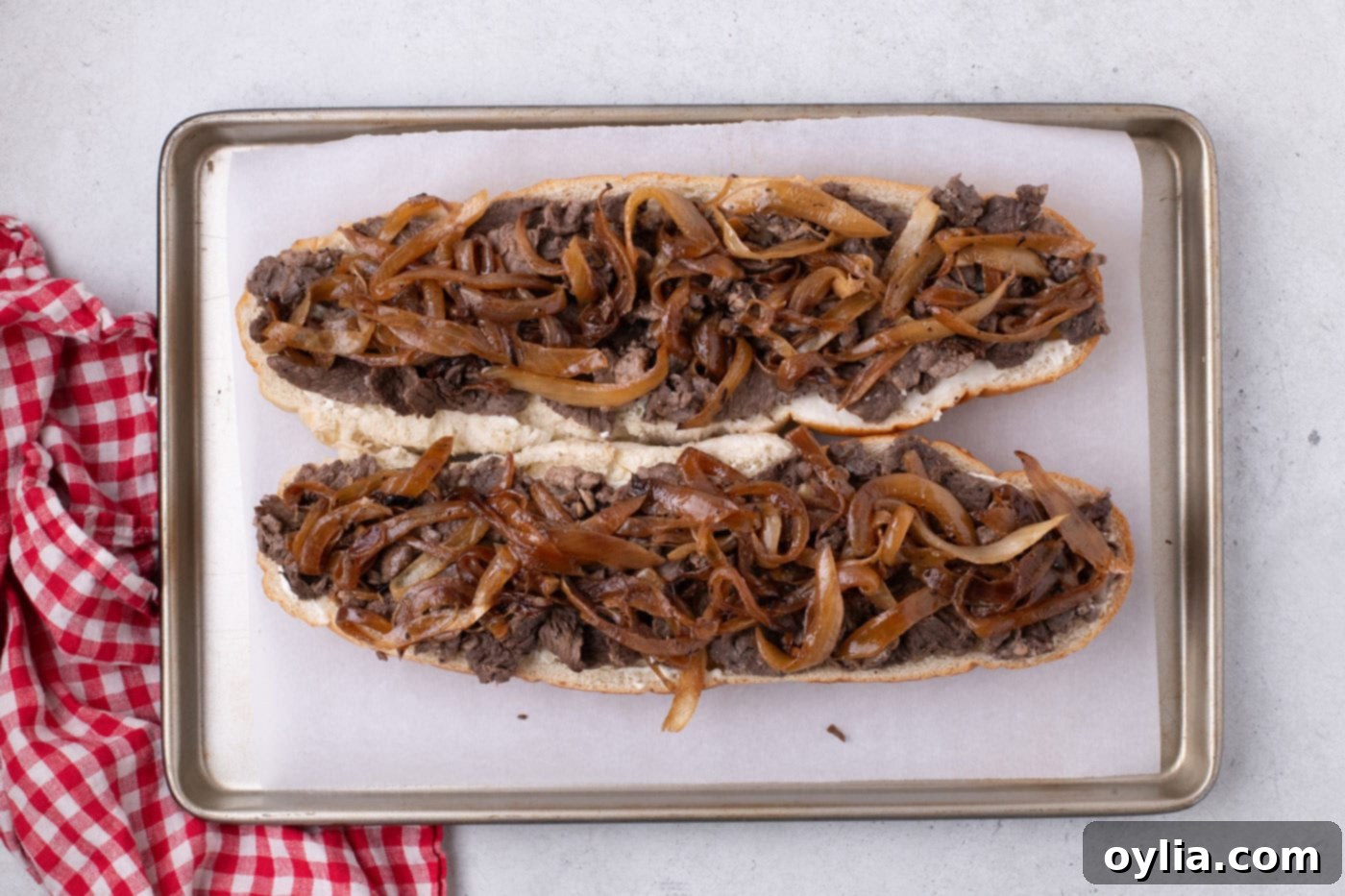 Caramelized onions layered on top of cooked steak on a French bread loaf.
