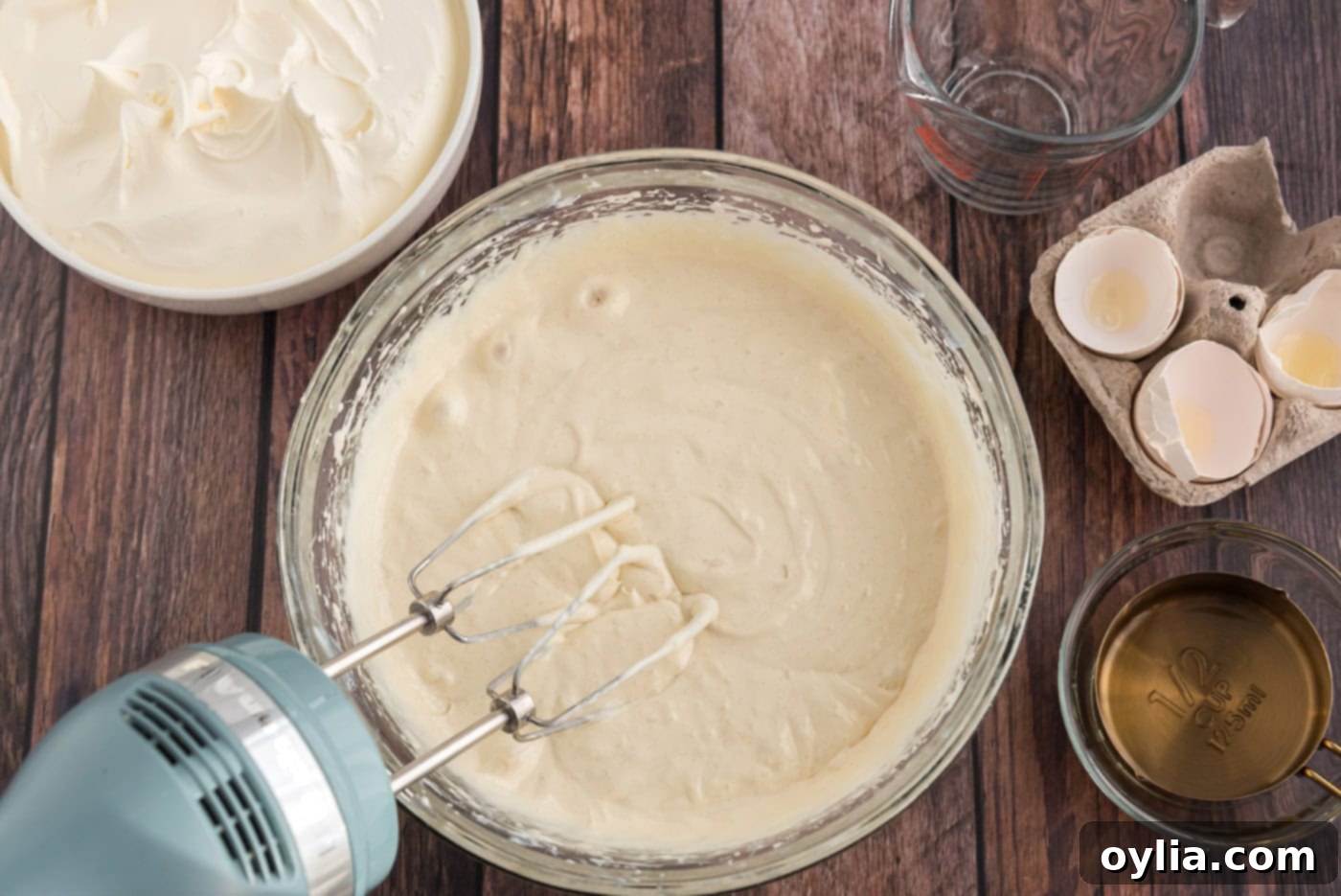Prepared cake mix batter in a bowl with a mixer, ready to be poured into a baking pan.