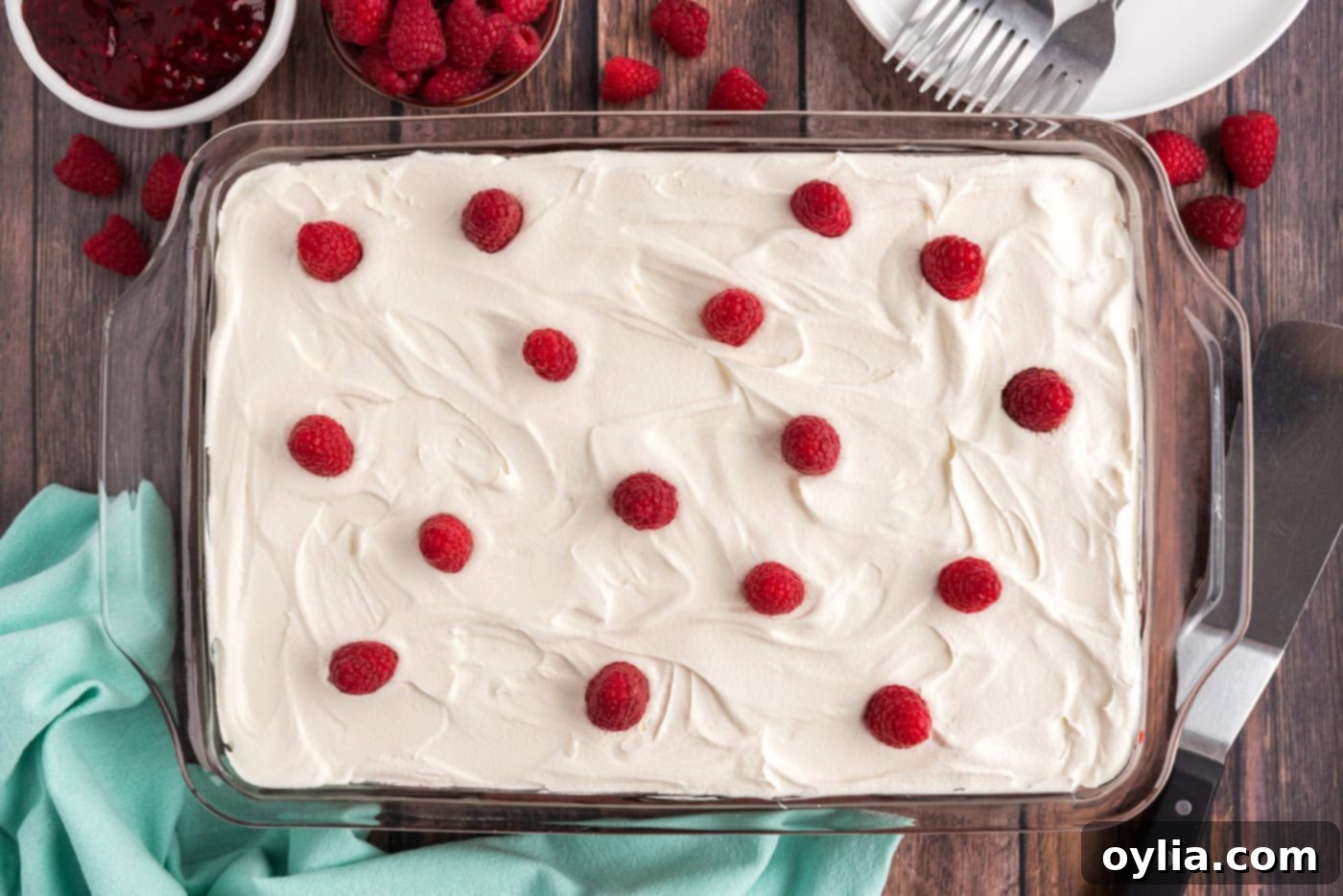 A finished Raspberry Poke Cake topped with a generous layer of fresh raspberries and Cool Whip.