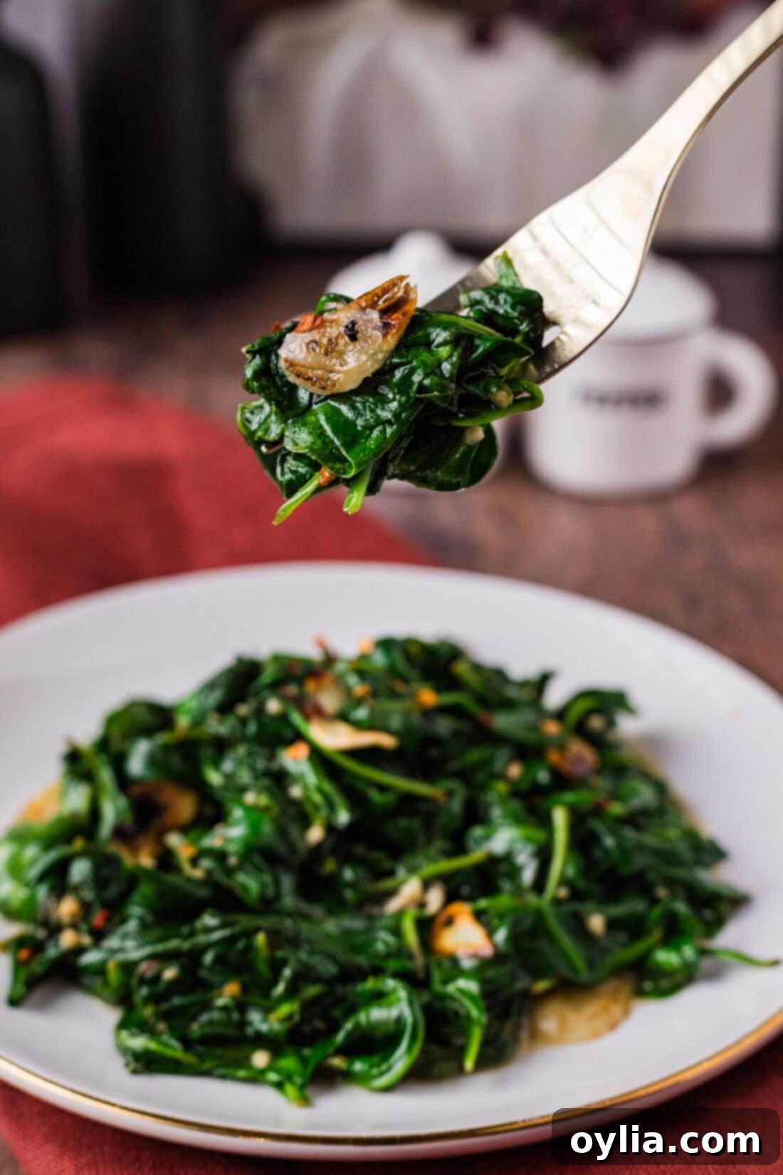 Fork of Stir Fried Spinach held above a plate of Stir Fried Spinach