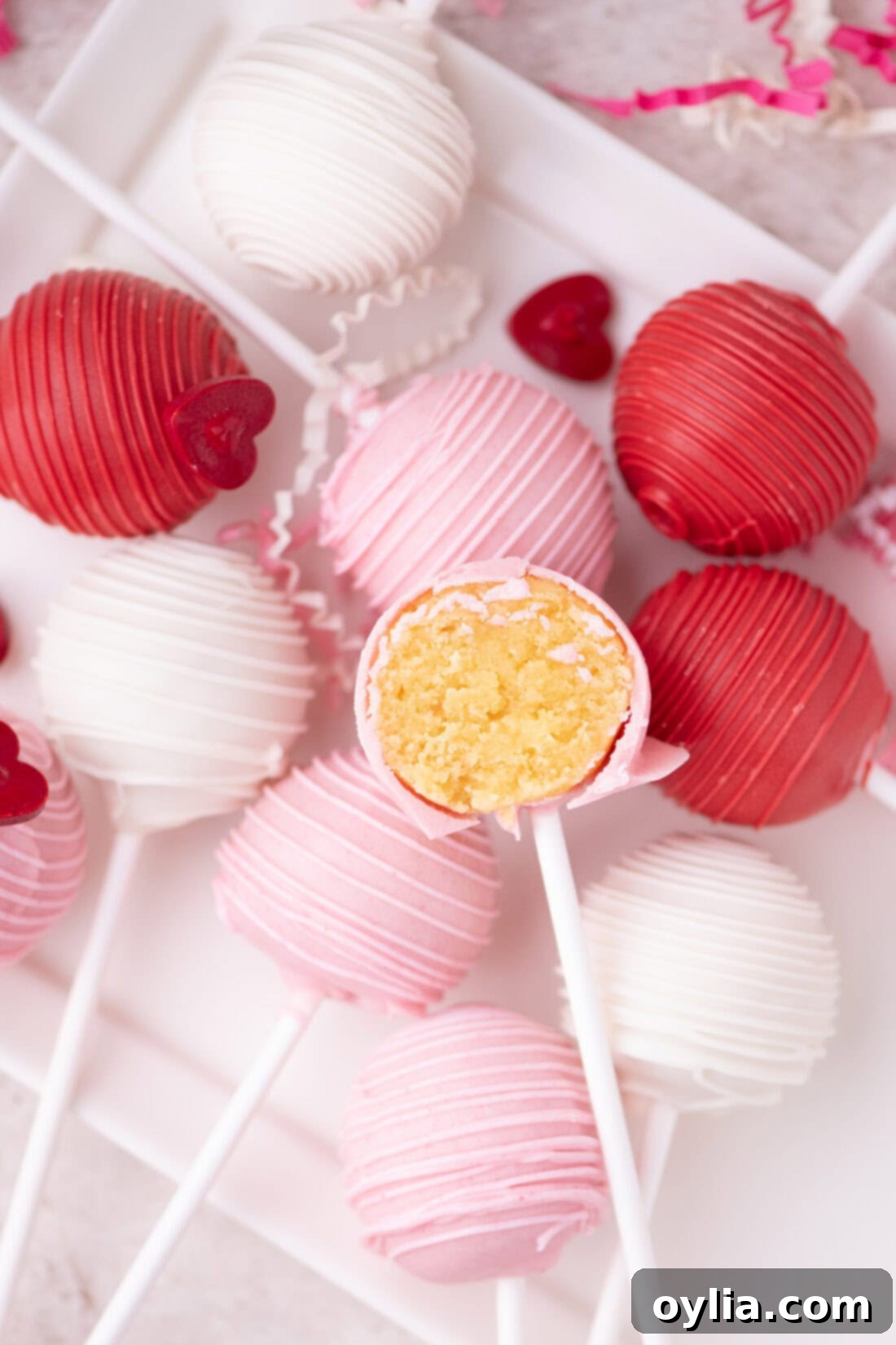 Love-Filled Valentine Cake Pops 3 A plate of Valentine Cake Pops, with one cut in half to reveal the moist, delicious cake interior, highlighting their perfect texture and festive appeal.