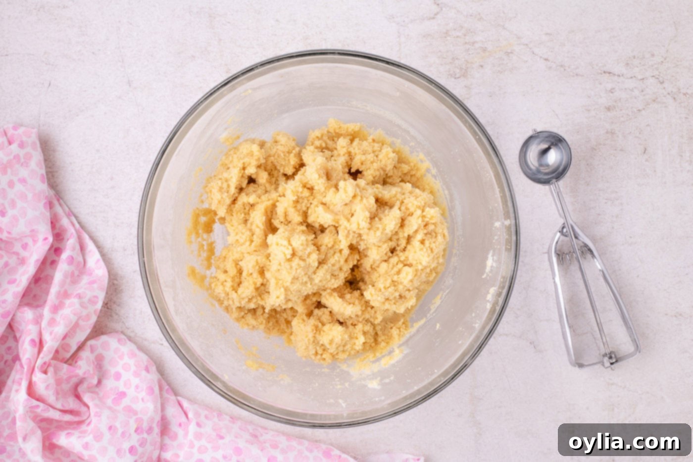 crumbled cake being mixed with vanilla frosting in a bowl, forming a pliable dough
