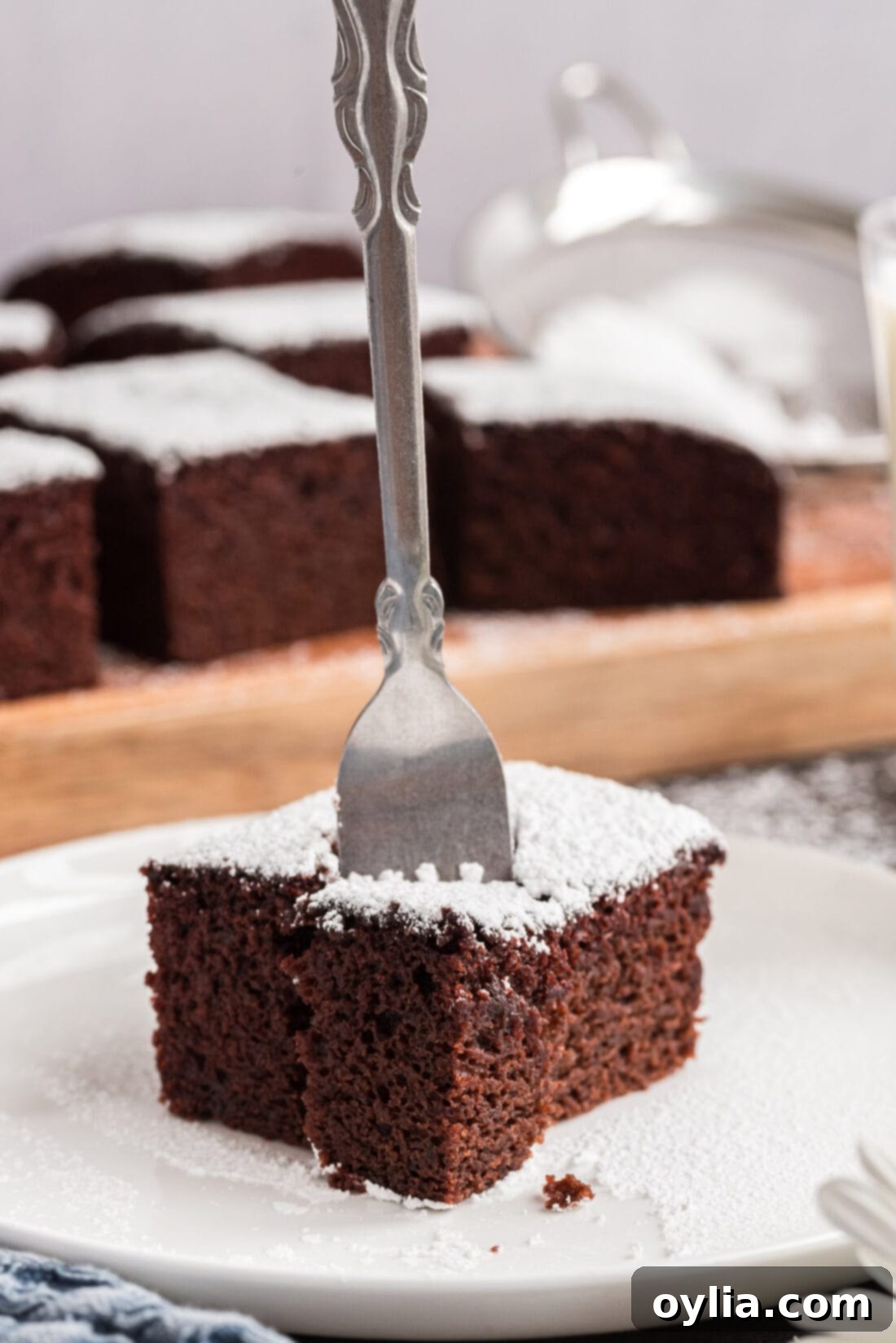 Fork in a square of Wacky Cake, showcasing its moist, rich texture.