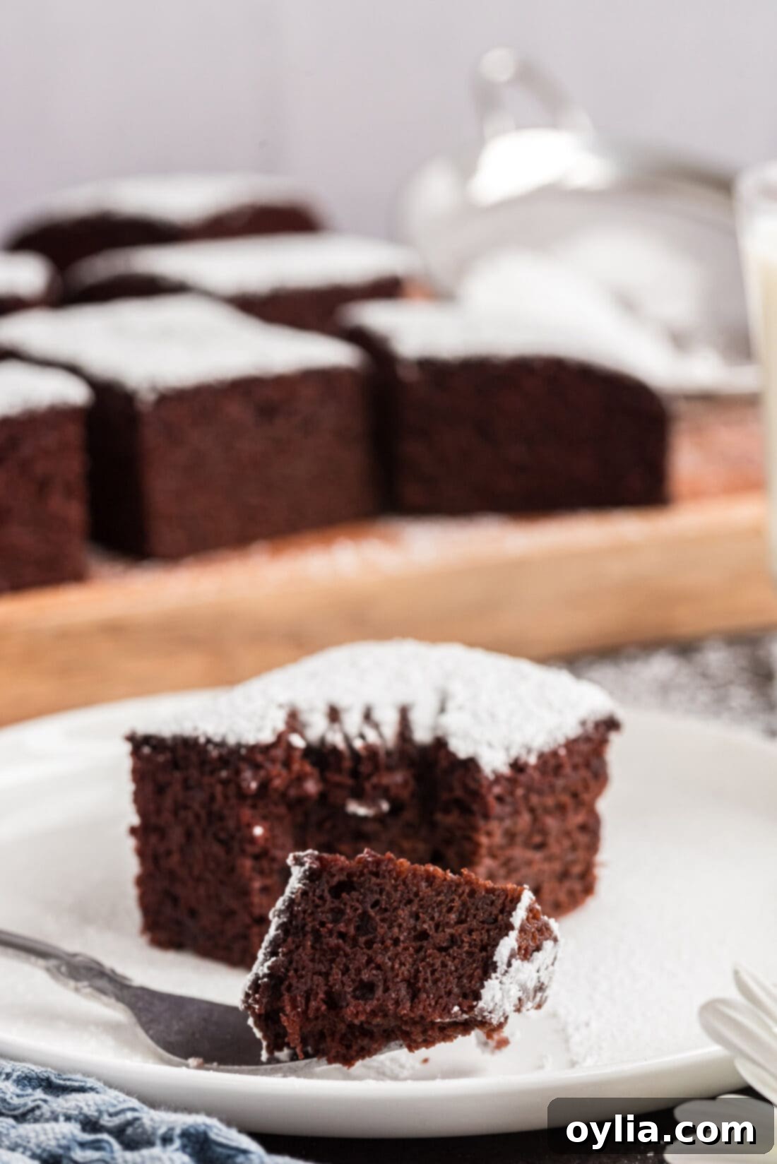 A fork taking a bite out of a piece of Wacky Cake, with another square in the background.