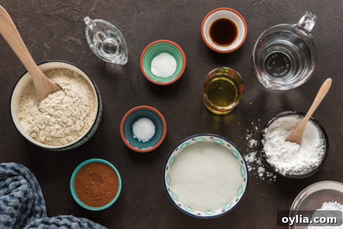 A flat lay image displaying all the simple ingredients required to make Wacky Cake, including flour, sugar, cocoa, oil, vinegar, and vanilla.