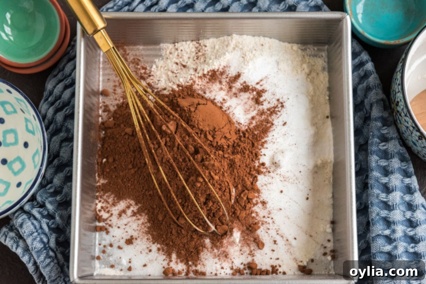 Whisking cocoa powder with flour, sugar, salt, and baking powder in a baking pan.