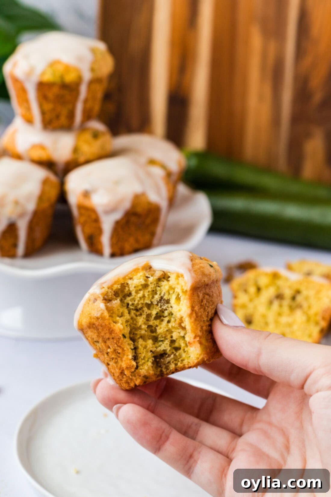 Zucchini Muffins in a Flash 10 Hand holding a Shortcut Zucchini Muffin with a bite taken out, showing the moist interior