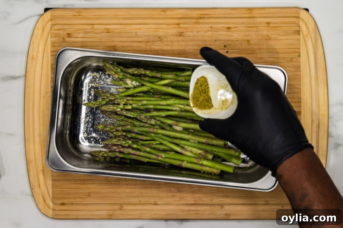seasoning asparagus in a pan with lemon pepper