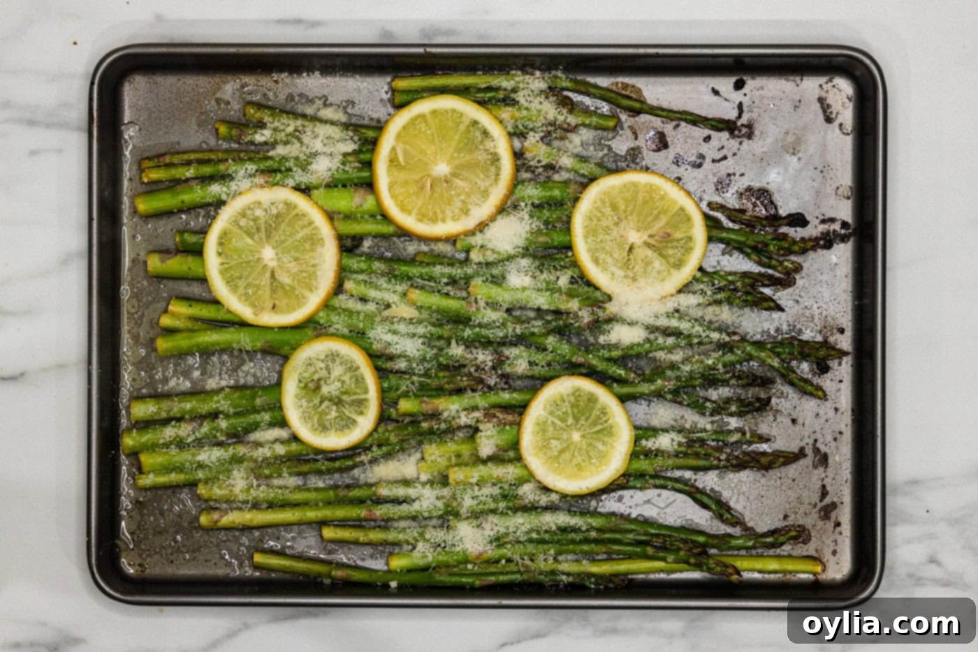 lemon asparagus on a baking pan wih parmesan cheese