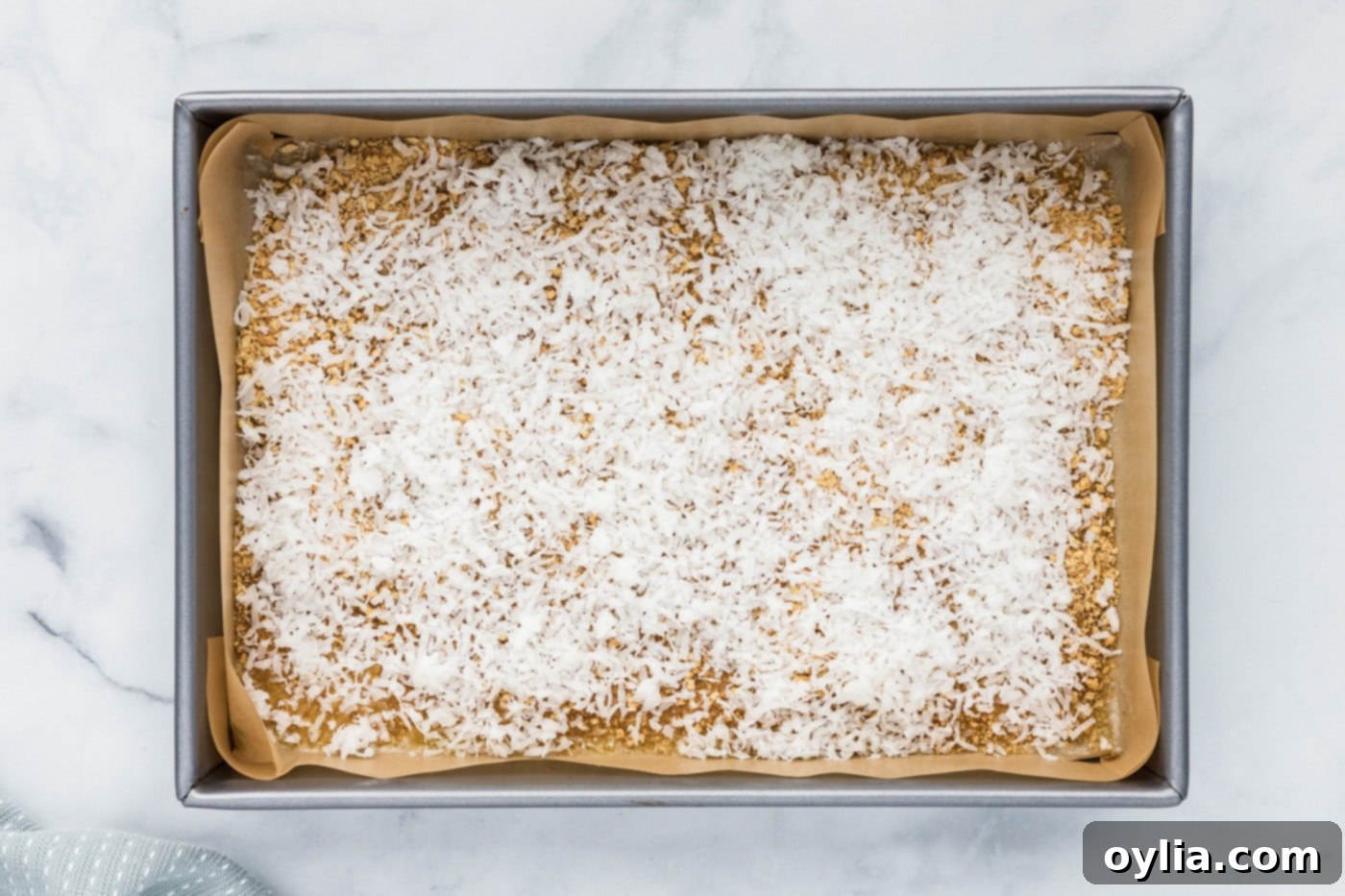 shredded coconut sprinkled over graham crumbs and melted butter in a baking pan