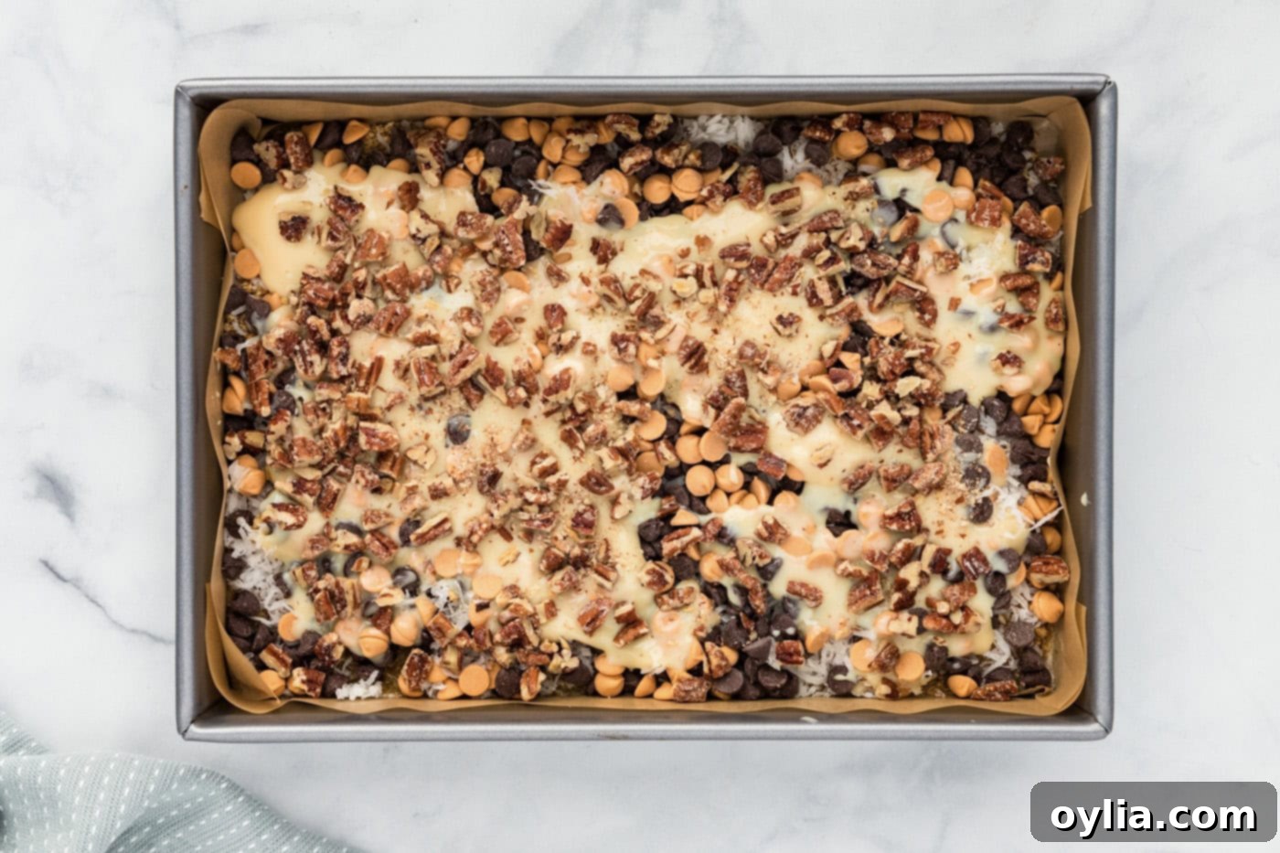 chopped pecans sprinkled over magic bars in a baking dish