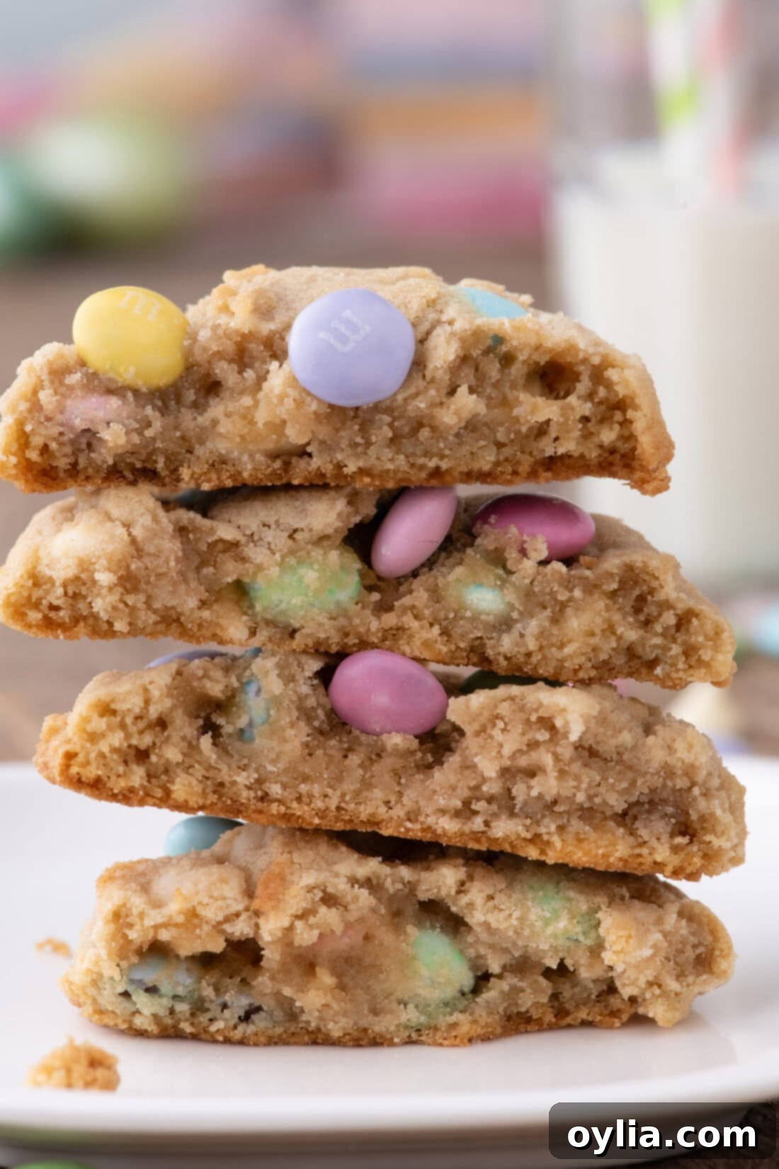 A stack of Easter M&M Cookies, with one broken in half to reveal the soft, chewy interior and melty white chocolate chips.