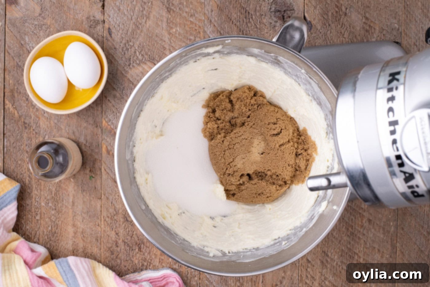 Sugars being added to the beaten butter mixture in a stand mixer.