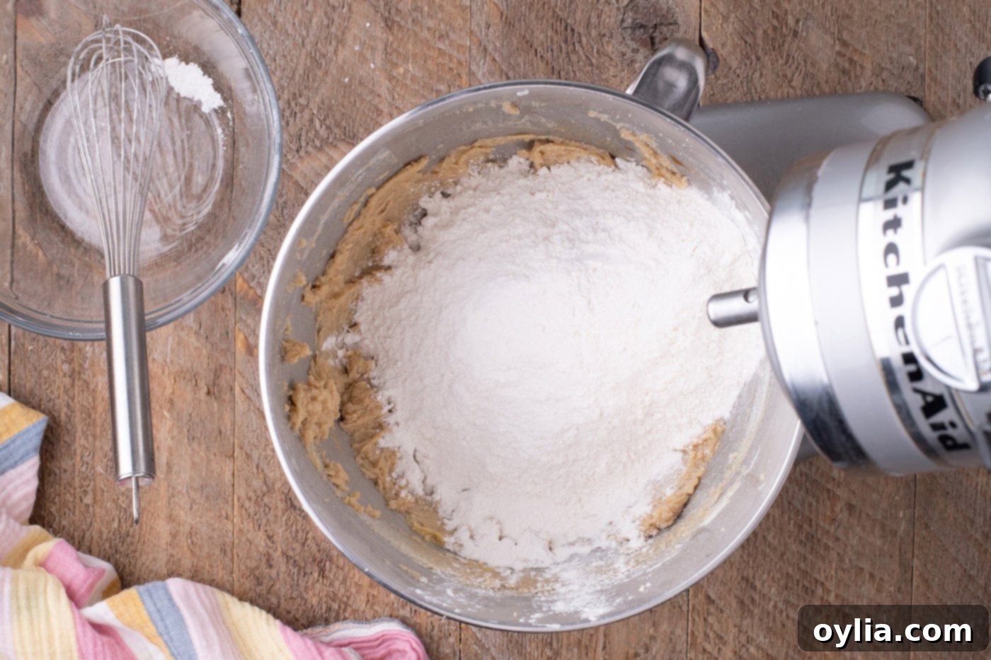 Dry ingredients being added to wet ingredients in a stand mixer bowl.