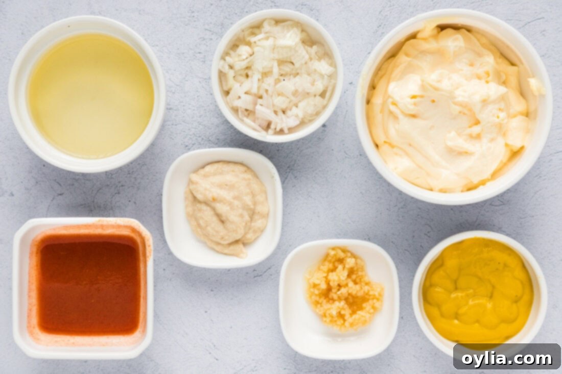 A vibrant selection of fresh remoulade sauce ingredients, including rich mayonnaise, various mustards, pungent horseradish, fiery hot sauce, and bright lemons, arranged on a rustic surface