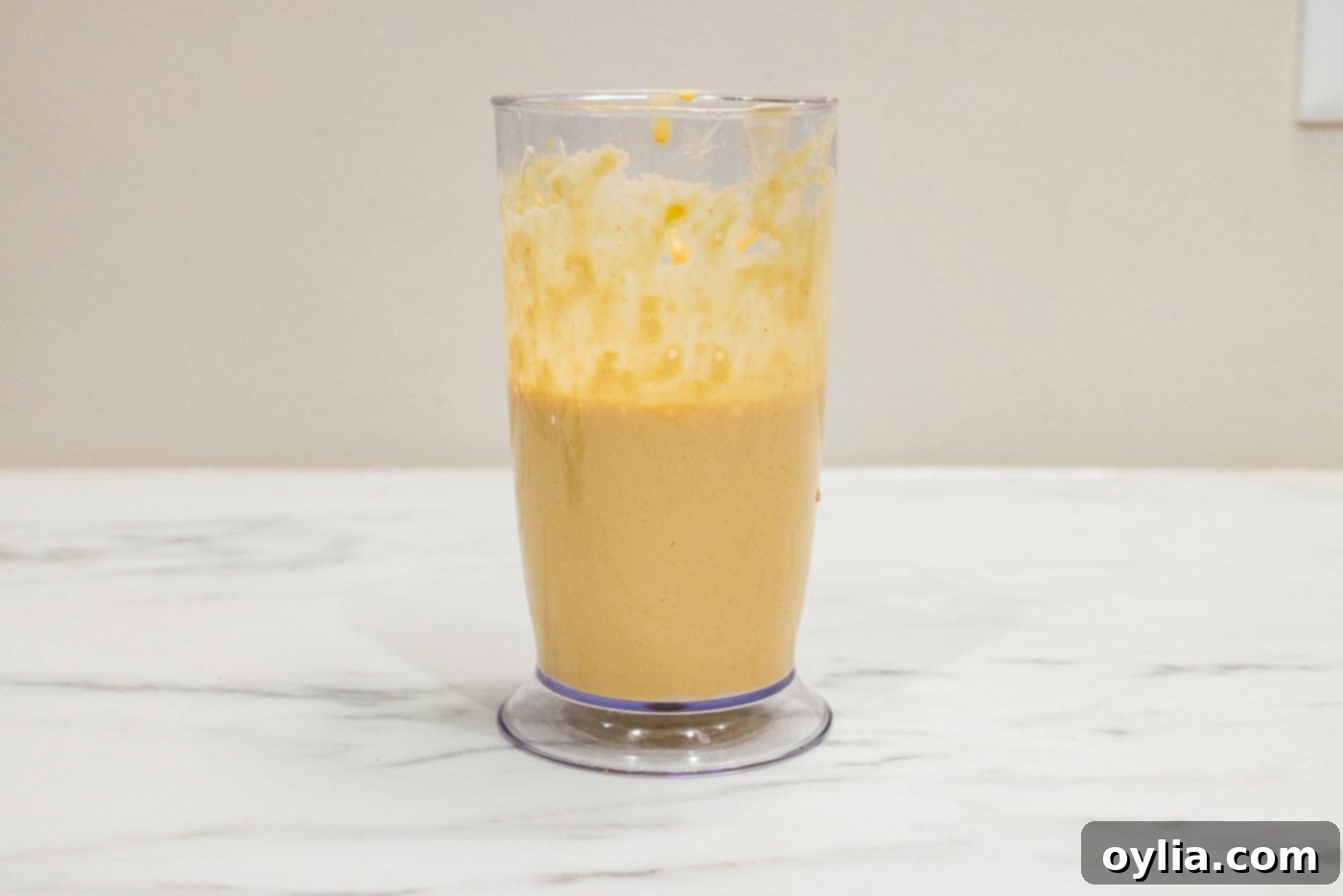 An immersion blender actively mixes the remoulade sauce ingredients in a tall cup, creating a perfectly smooth and creamy condiment.