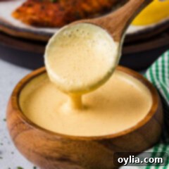 Close-up photo of a spoon drizzling creamy Remoulade Sauce into a white bowl, showcasing its smooth texture and rich color
