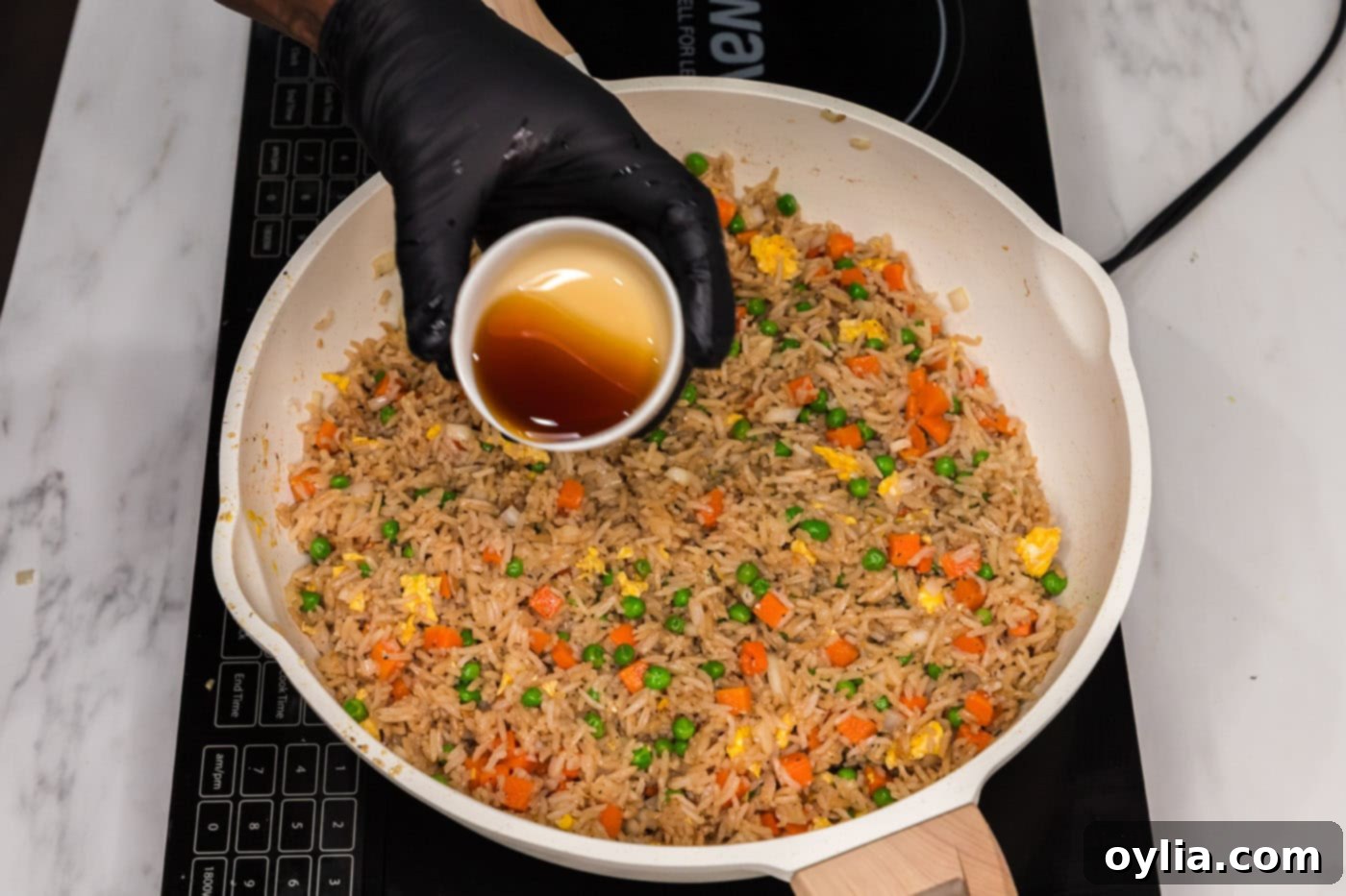 pouring sesame oil into v vegetable fried rice