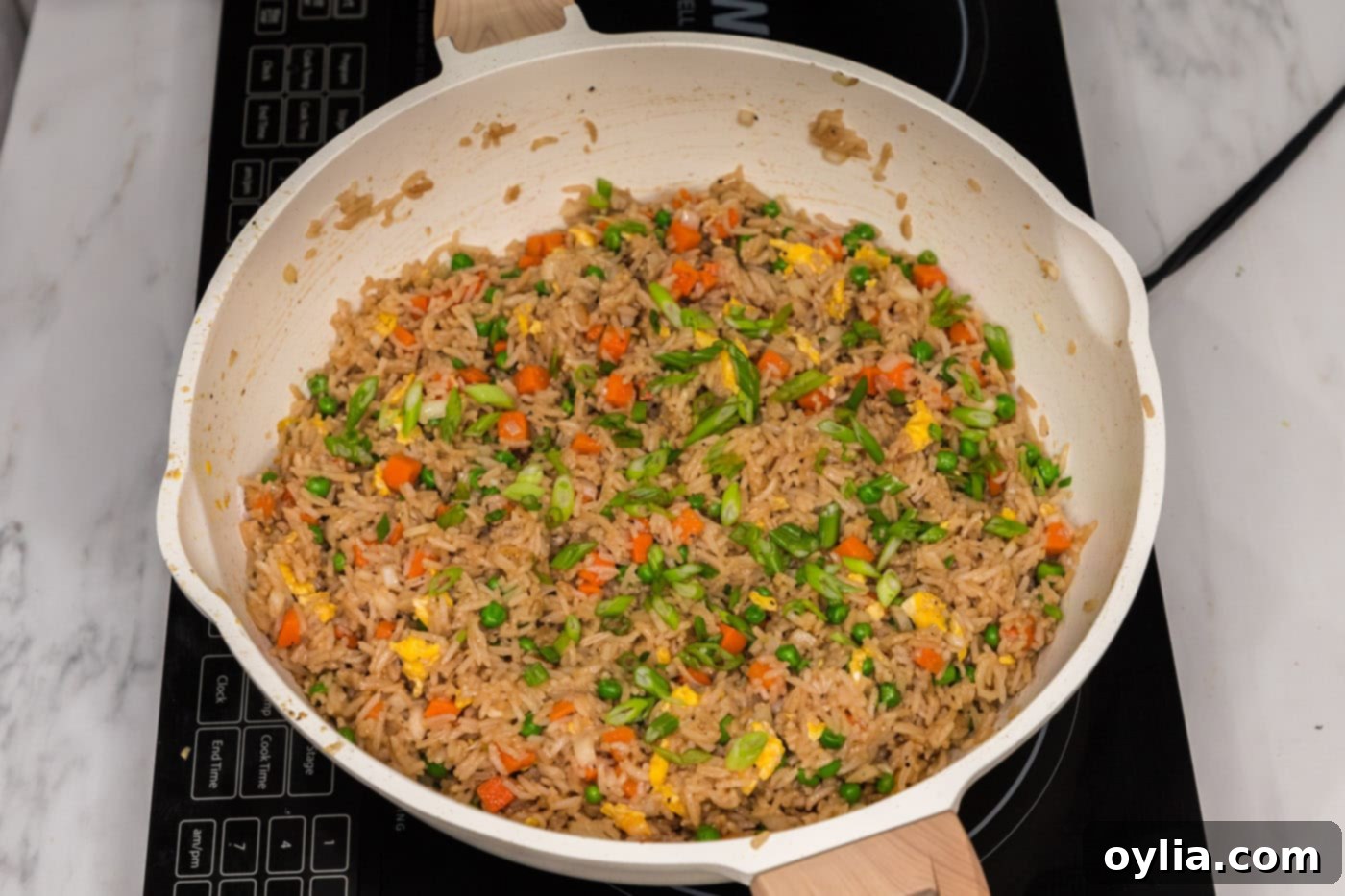 sliced green onions on top of vegetable fried rice in a skillet