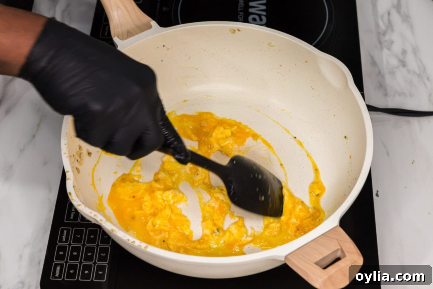 scrambling eggs in a skillet with a rubber spatula