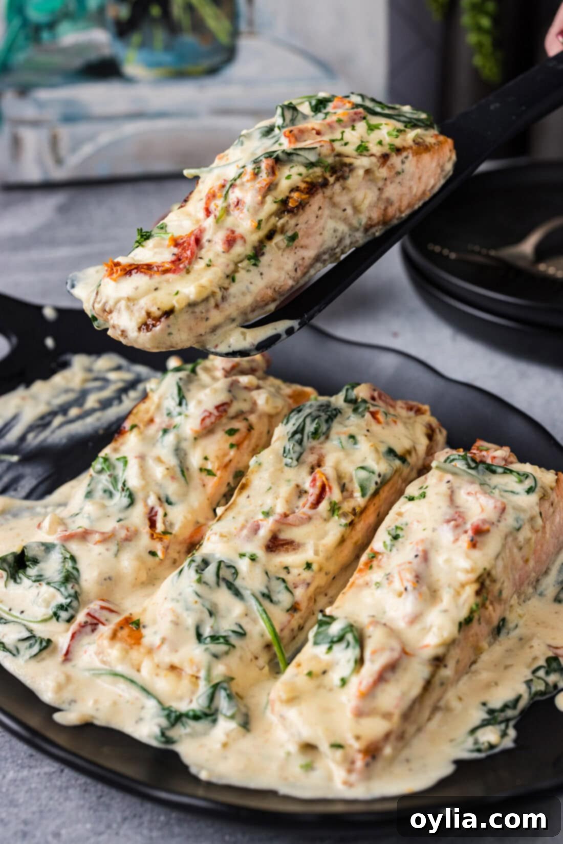 Spatula lifting up a perfectly cooked Tuscan Salmon filet, showcasing its flaky texture and creamy sauce.