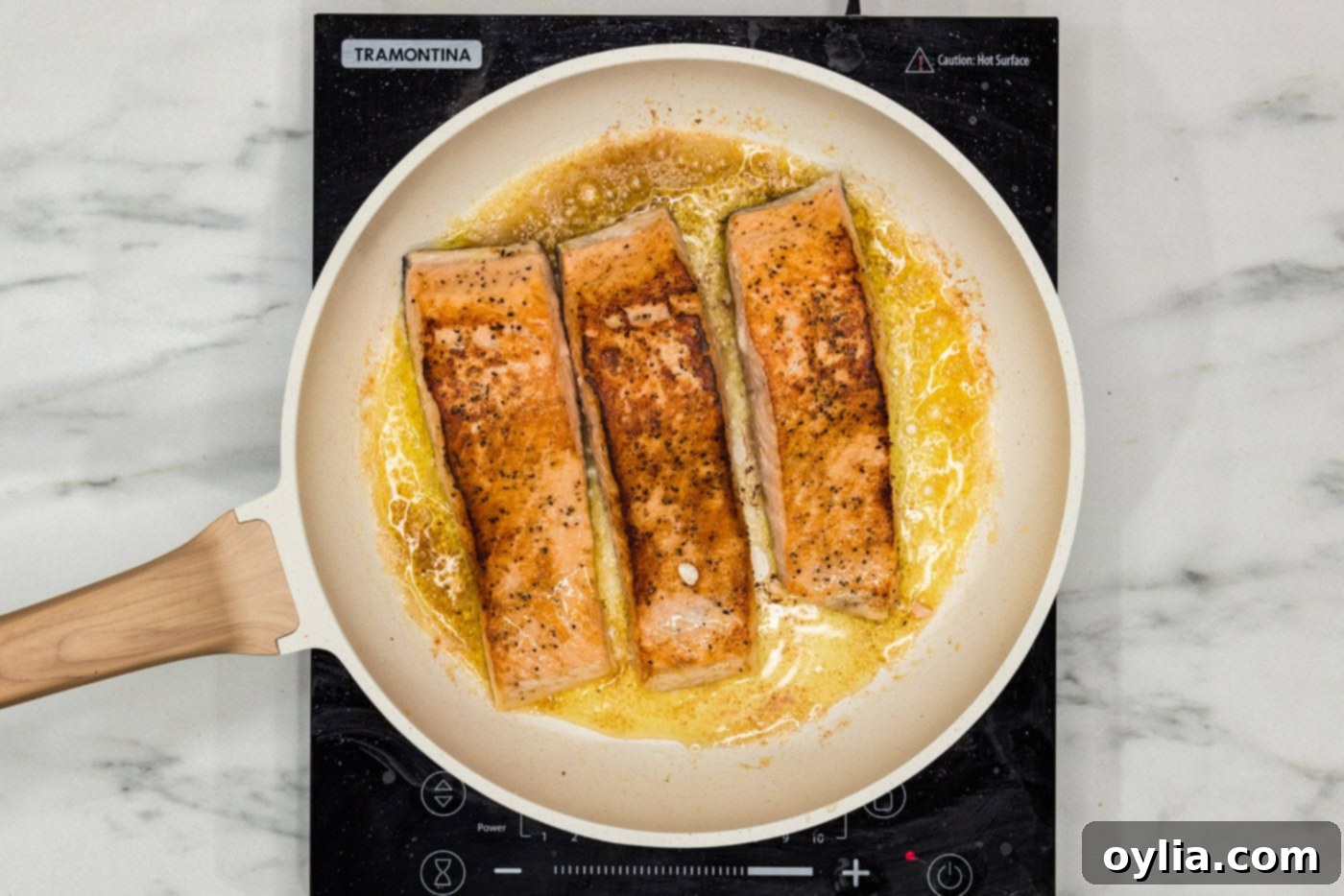 Salmon fillets flipped over in a skillet, showcasing their nicely browned flesh side.
