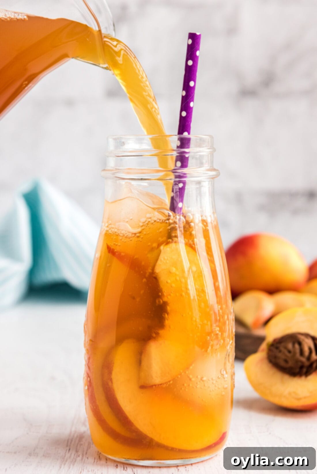 Pouring refreshing homemade peach iced tea into a glass with ice