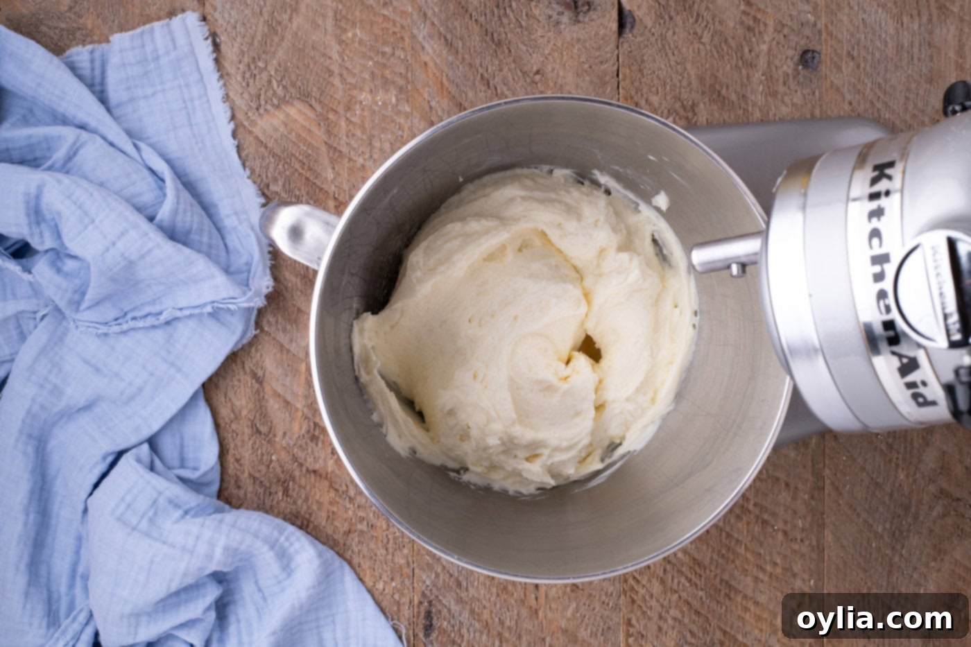 Lemon cream cheese frosting being mixed to a smooth consistency in a stand mixer