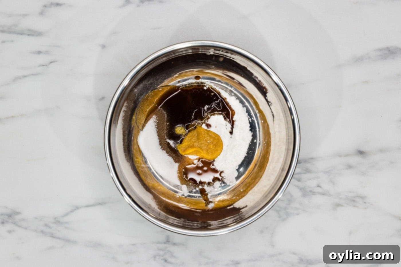 A bowl filled with the liquid ingredients for lobster sauce, including cornstarch, sesame oil, and oyster sauce, being whisked together