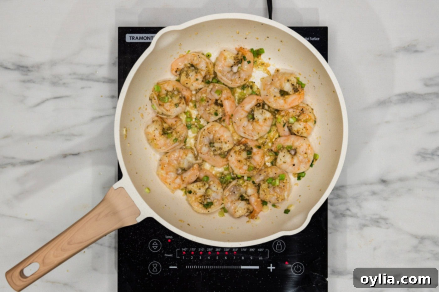 Pink, perfectly cooked shrimp in a skillet with vibrant green onions, ready for the sauce