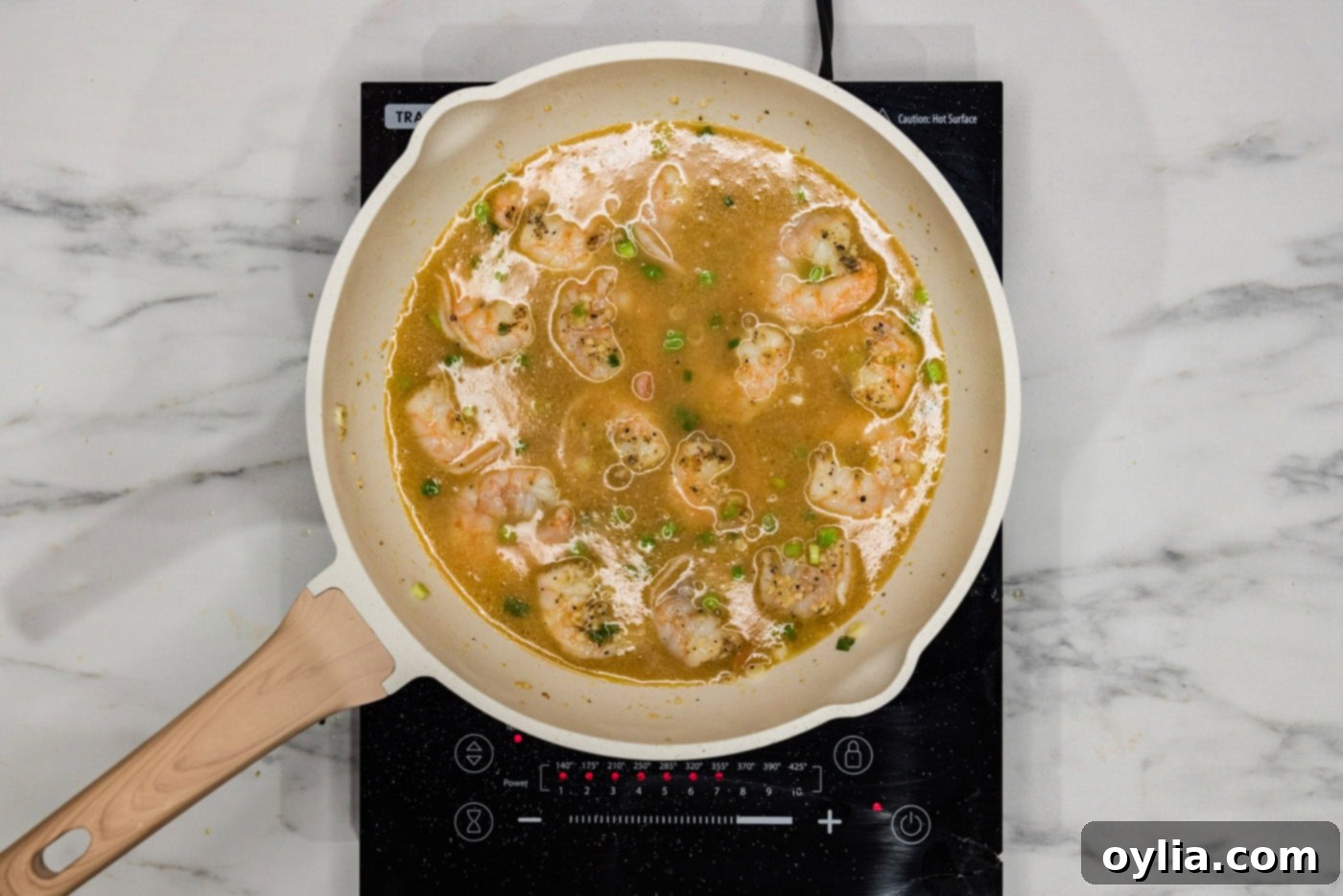 The chicken base sauce mixture being poured into a skillet with shrimp, beginning to thicken