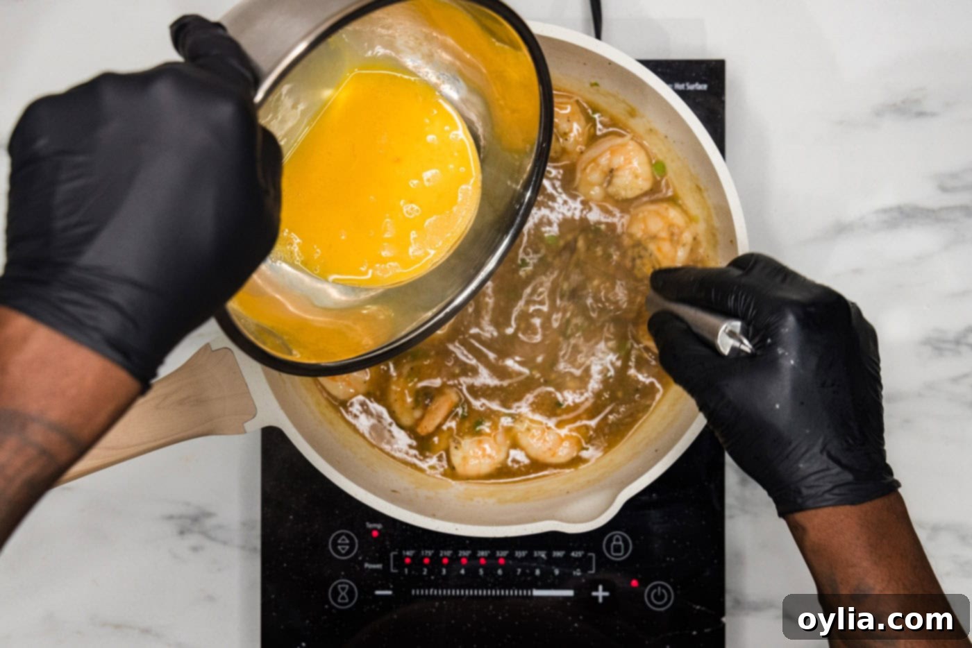 Whisked egg mixture slowly drizzled into a skillet of shrimp and sauce, creating delicate egg ribbons