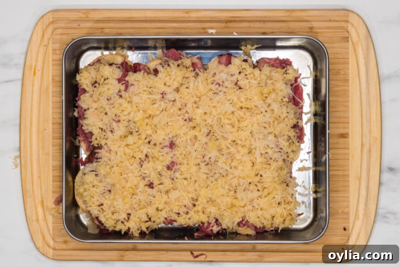 Sauerkraut spread evenly over the corned beef layer on the slider buns