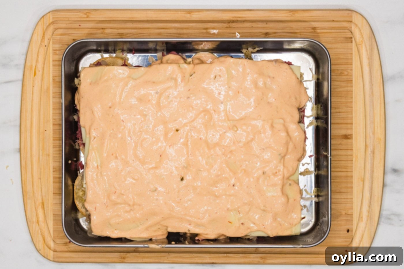 Thousand Island dressing drizzled over the cheese layer of the Reuben sliders