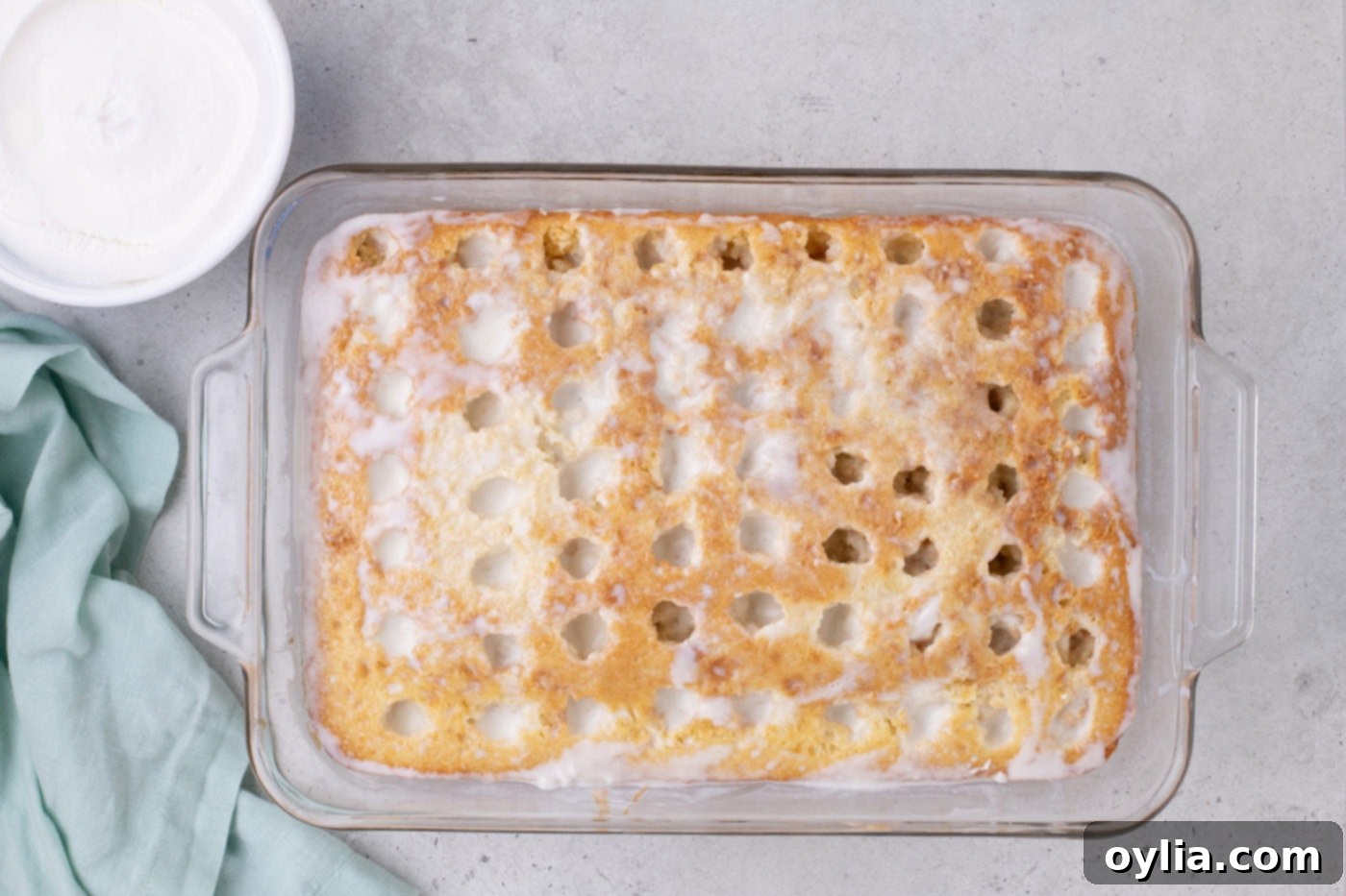 coconut cream filling poured over holes in a cake