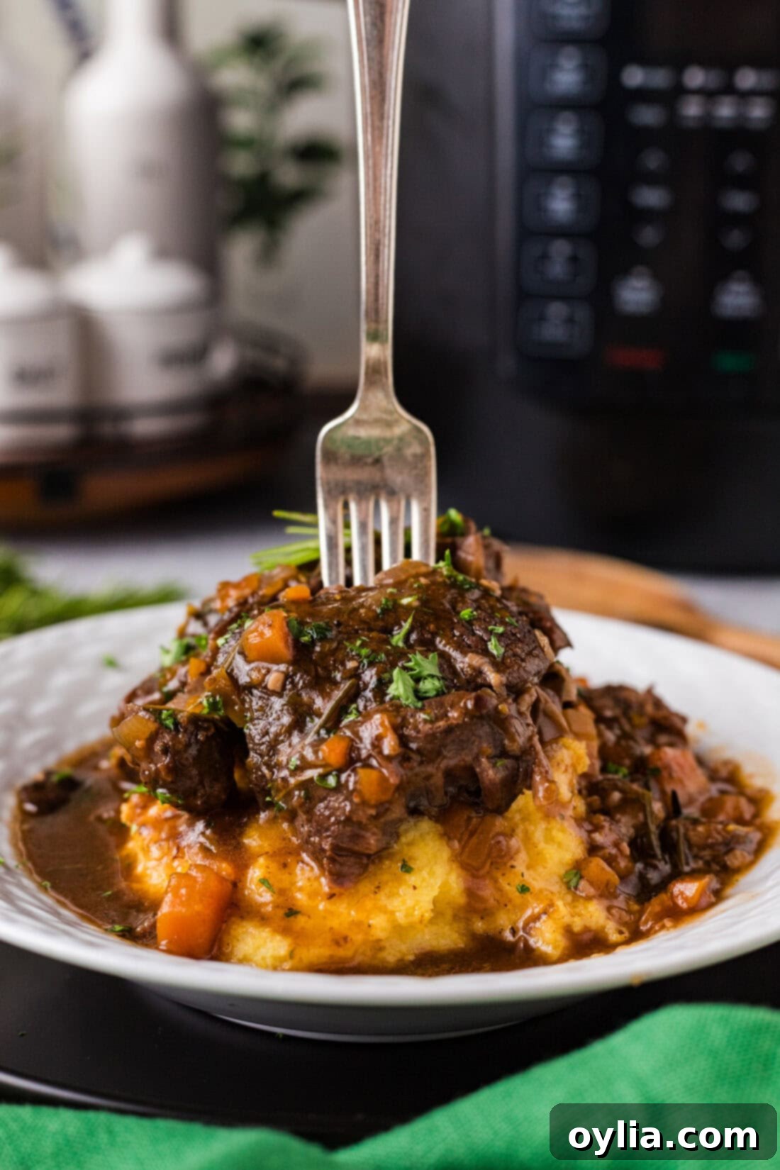 Fork stuck into incredibly tender Instant Pot Beef Shanks plated over creamy mashed potatoes, ready to be enjoyed.