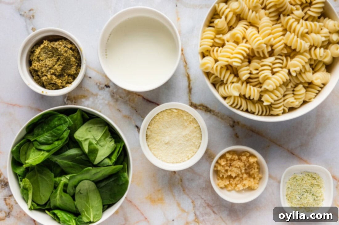 Fresh Pesto Pasta 4 A flat lay of fresh ingredients for Pesto Pasta, including pasta, pesto, spinach, garlic, and cream.
