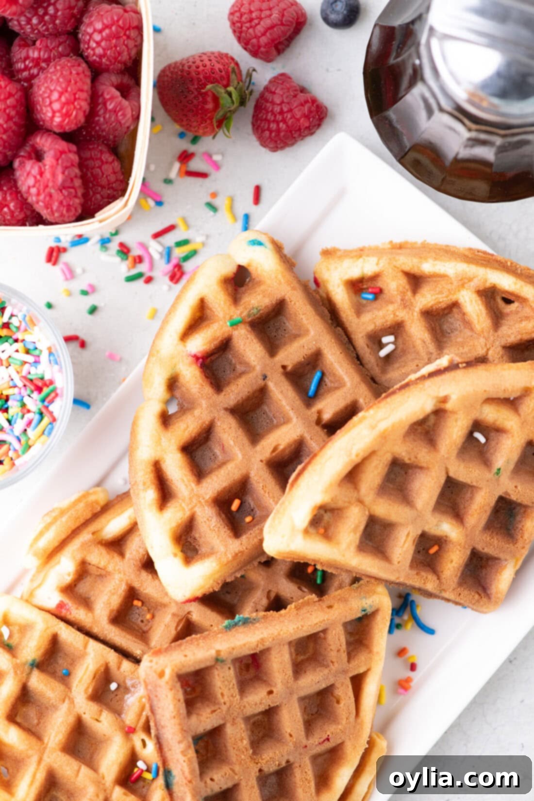 Cake Mix Waffles cut into triangles on a platter with sprinkles and syrup